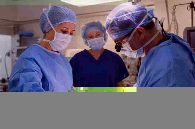 Surgical first assist in scrubs working beside a surgeon at the operating table