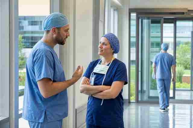Surgical technologist in scrubs standing in a bright outpatient surgery center hallway