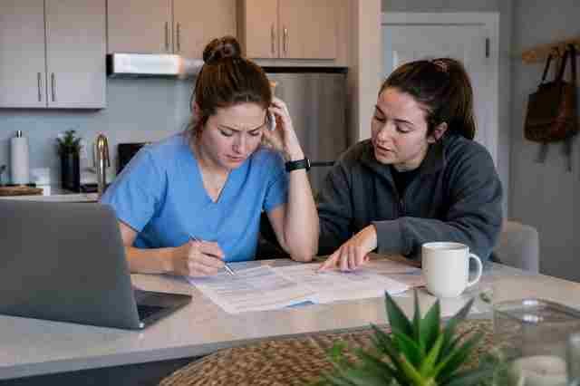 Surgical technologist in scrubs reading a job posting on a laptop in a hospital lounge