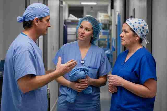Surgical technologist in scrubs standing at an operating table with a surgeon during a case