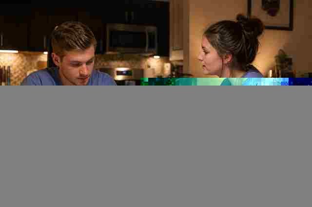 Surgical tech student in scrubs studying for the CST exam with notes at a table